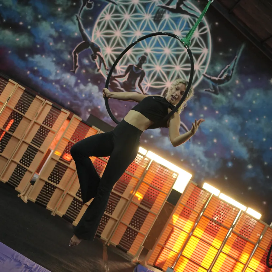 Adult aerial class in Kerobokan, Bali — an adult aerialist working the hoop above the training floor